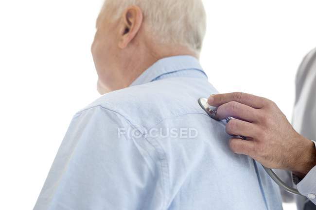 Мужчина-врач осматривает старшего пациента стетоскопом . — стоковое фото