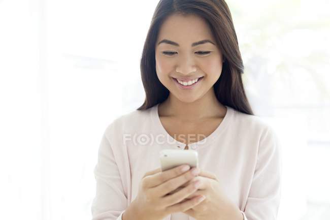 Молода жінка використовує смартфон і посміхається . — стокове фото