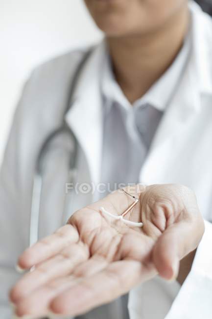 Médica mulher segurando dispositivo intrauterino, close-up . — Fotografia de Stock