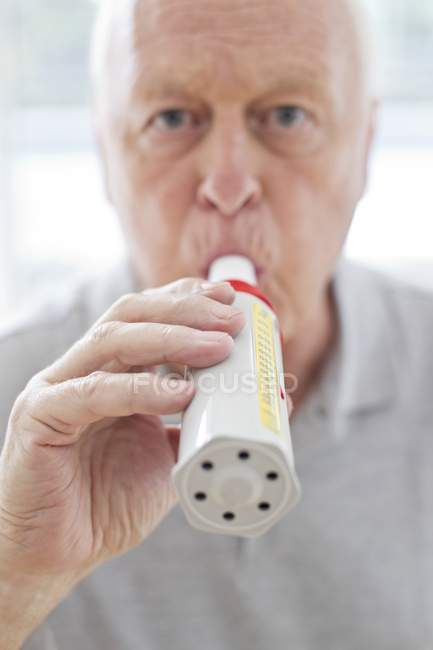 Homme âgé utilisant débitmètre de pointe et regardant à la caméra . — Photo de stock