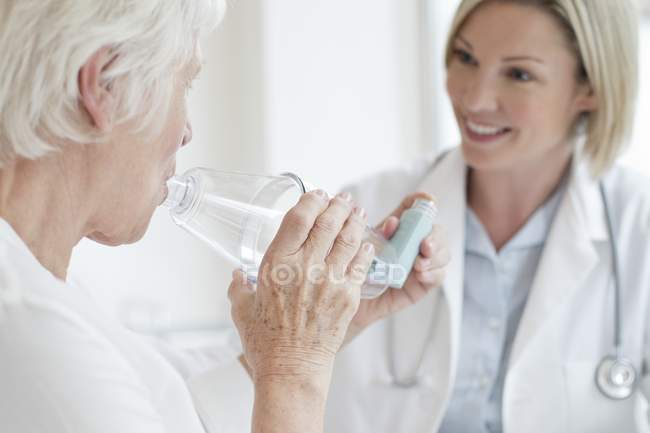 Seniorin mit Inhalator unter Beobachtung einer Ärztin. — Stockfoto
