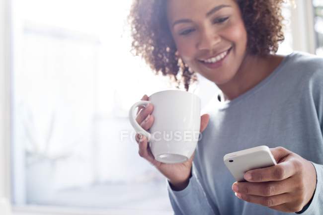 Mujer feliz con café y teléfono celular - foto de stock