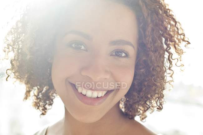 Mujer con el pelo rizado sonriendo a la cámara - foto de stock