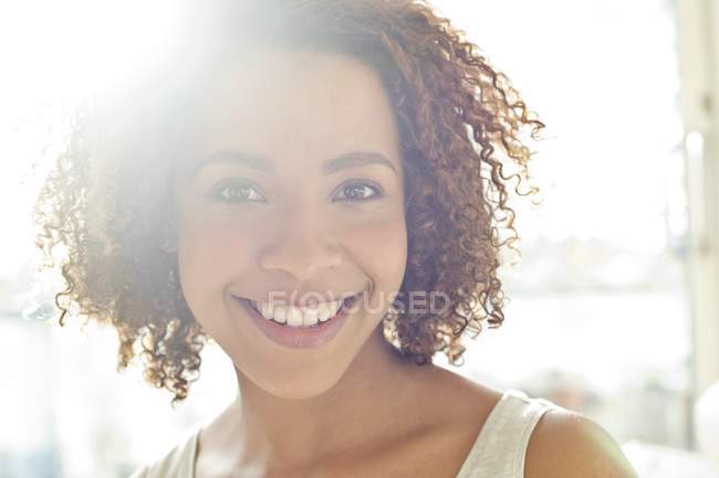 Женщина с вьющимися волосами улыбается в камеру — стоковое фото