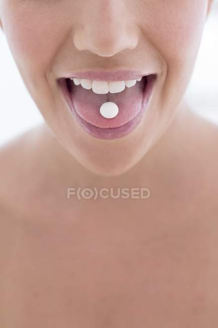 Junge Frau mit Pille auf der Zunge, Nahaufnahme. — Stockfoto