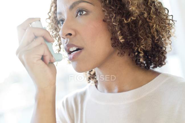 Mujer que usa inhalador - foto de stock