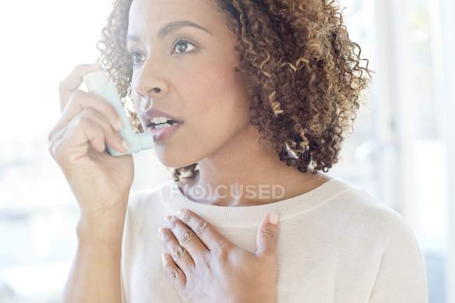 Mujer que usa inhalador - foto de stock