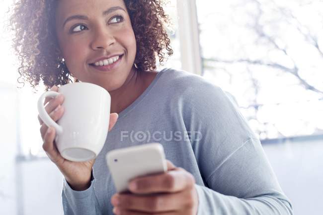 Счастливая женщина с кофе и сотовый телефон — стоковое фото