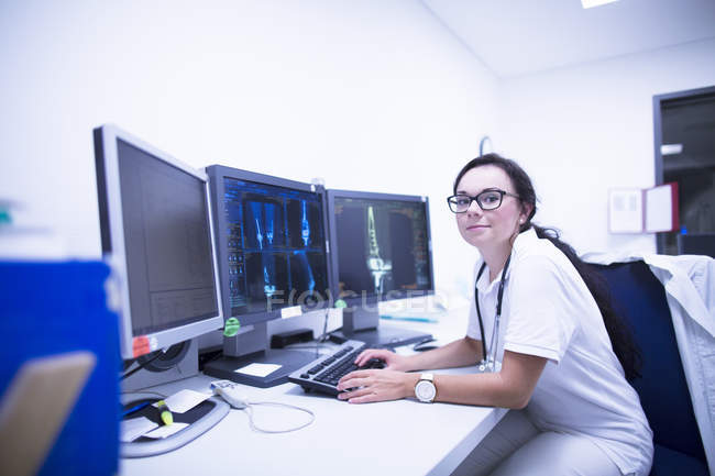 Hospital radiologist sitting at desk in front of CT scans. — Stock Photo