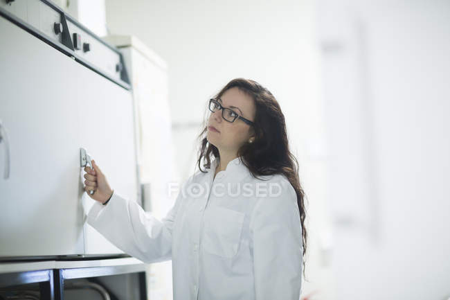 Femme scientifique ouvrant le cabinet dans un laboratoire de recherche . — Photo de stock