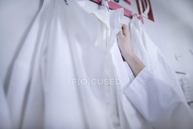 Close-up of female hand reaching for lab coat. — Stock Photo
