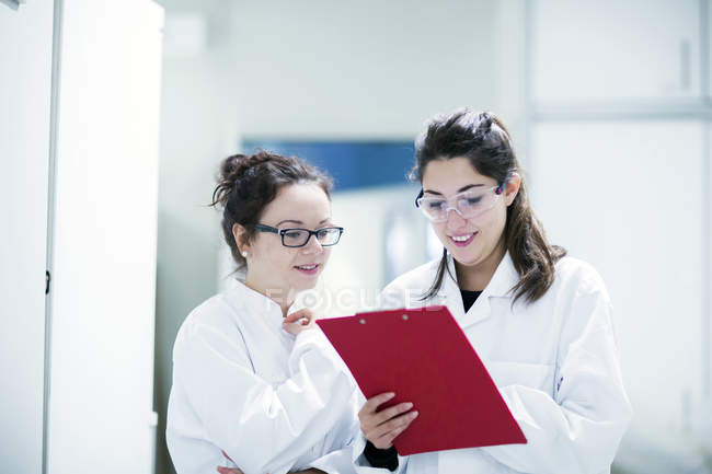 Cientistas do sexo feminino observando notas em laboratório . — Fotografia de Stock