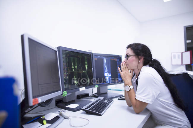 Radióloga que estudia tomografía computarizada en monitores . - foto de stock