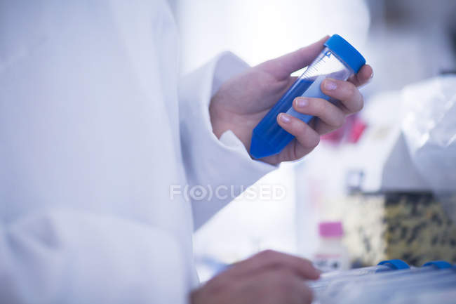 Close-up of hands of scientist holding test tube. — Stock Photo