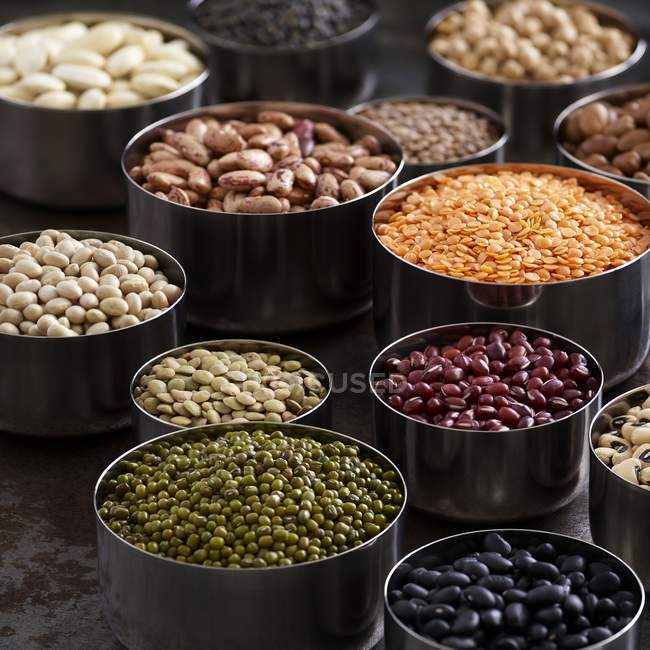 Legumes in metal bowls on rustic table. — Stock Photo