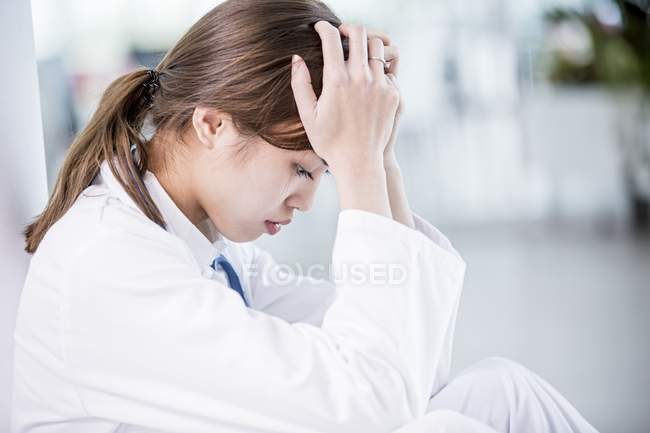 Female doctor with head in hands. — Stock Photo