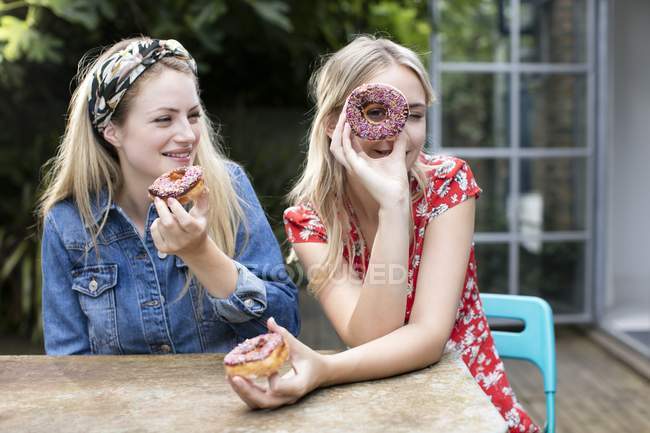 Дві жінки позують з пончиками . — стокове фото