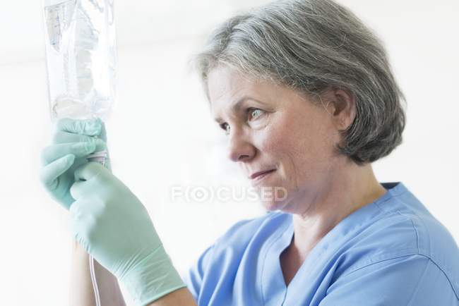 Female nurse preparing medical drip. — Stock Photo