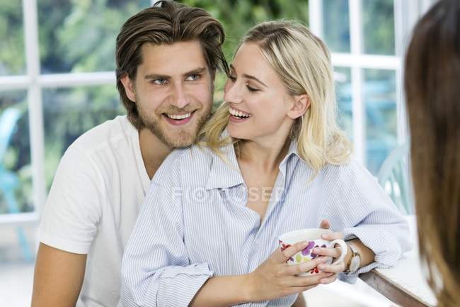 Young couple in kitchen smiling and having coffee. — Stock Photo