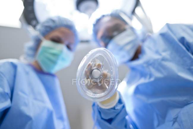 Female surgeons holding gas mask and looking in camera. — Stock Photo