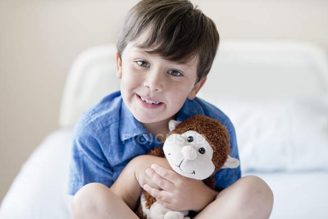 Boy with stuffed monkey in hospital bed. — Stock Photo