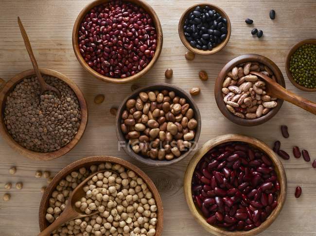 Pulses in wooden bowls with spoons, overhead view. — Stock Photo