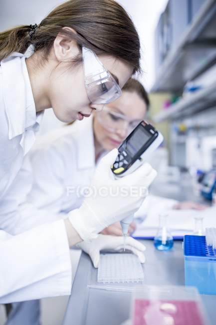 Laboratory assistants using pipette with digital display. — Stock Photo