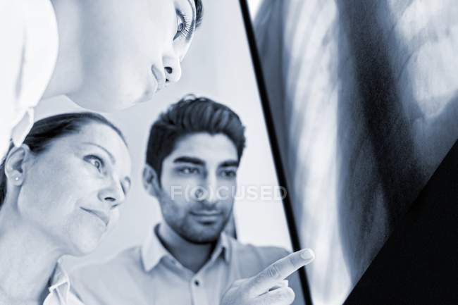 Médecins masculins et féminins regardant la radiographie de la cage thoracique . — Photo de stock
