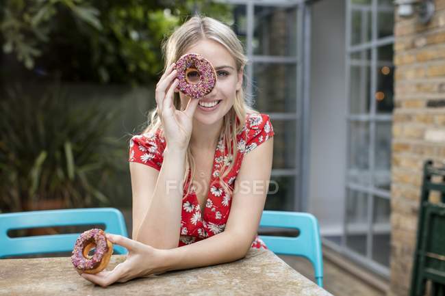 Junge Frau bedeckt Auge mit Donut. — Stockfoto