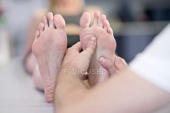 Fisioterapeuta masajeando los pies del paciente . - foto de stock