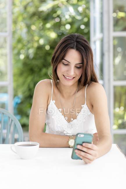 Молода жінка використовує смартфон за столом . — стокове фото