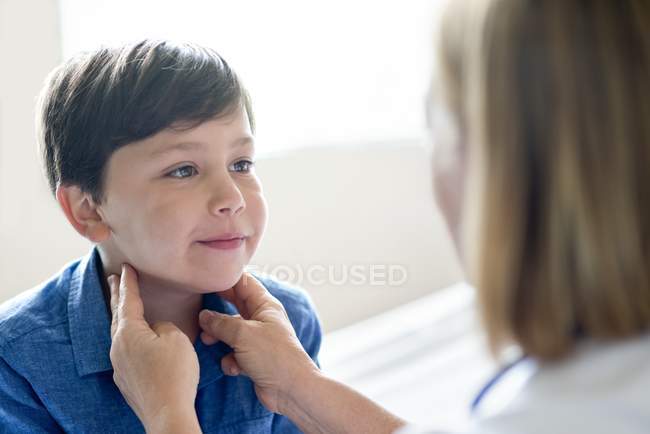 Enfermeira examinando glândulas menino com as mãos . — Fotografia de Stock