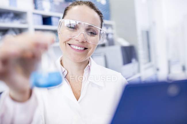 Female laboratory assistant holding chemical flask. — Stock Photo