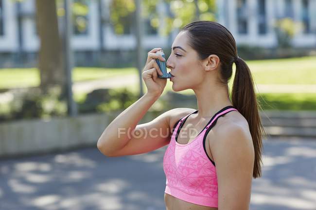 Молодая женщина в спортивной одежде с помощью ингалятора . — стоковое фото