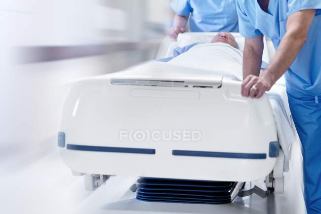 Two doctors pushing hospital bed with patient through corridor. — Stock Photo
