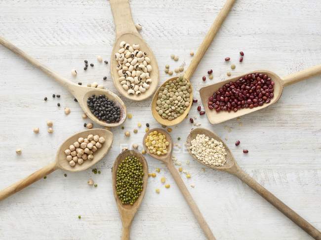 Legumes in wooden spoons, overhead view. — Stock Photo