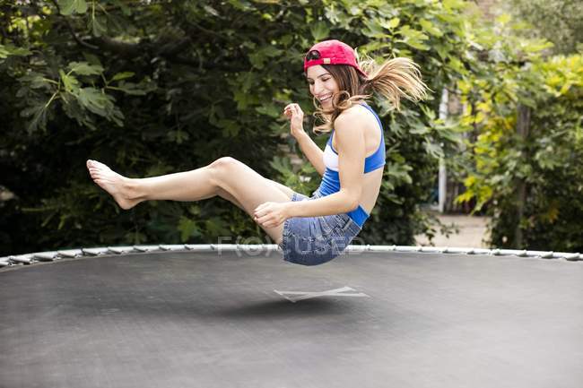 Frau hüpft auf Trampolin im Garten. — Stockfoto