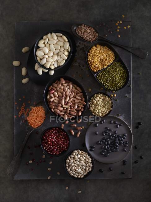 Pulses in bowls on dark background, overhead view. — Stock Photo
