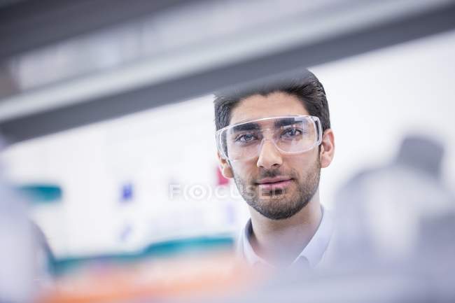 Assistente de laboratório masculino usando óculos de segurança . — Fotografia de Stock