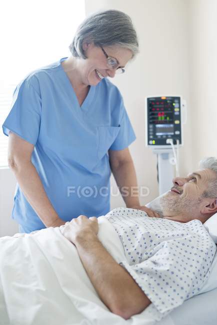 Женщина-медсестра разговаривает с пациентом на больничной койке . — стоковое фото