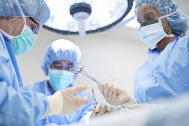 Enfermera pasando tijeras quirúrgicas al cirujano durante la operación
. - foto de stock