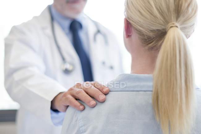 Male doctor with hand on female shoulder. — Stock Photo