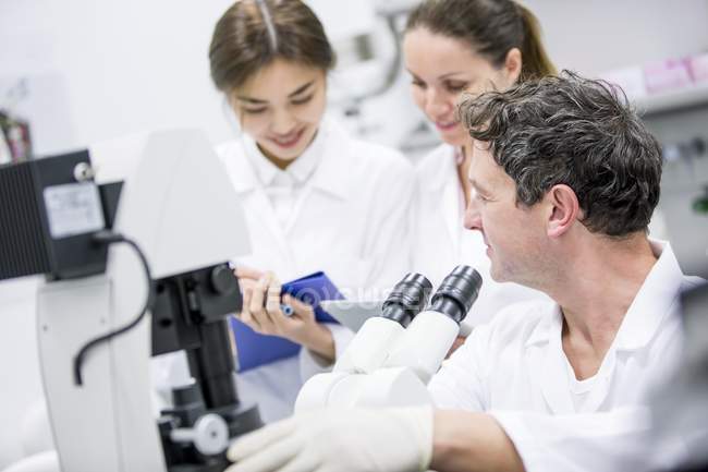 Cientistas trabalhando em laboratório com microscópio
. — Fotografia de Stock