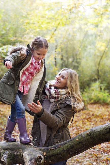 Family playing on tree trunk in woods in autumn. — Stock Photo