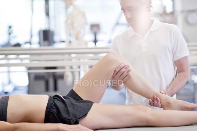 Fisioterapista massaggiando le gambe femminili . — Foto stock
