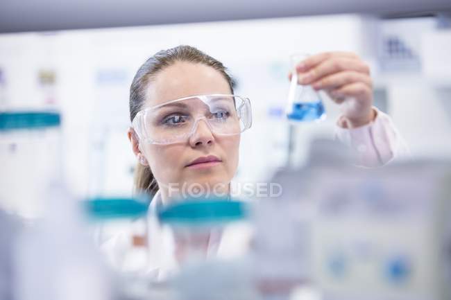 Assistante de laboratoire femelle tenant une fiole chimique . — Photo de stock