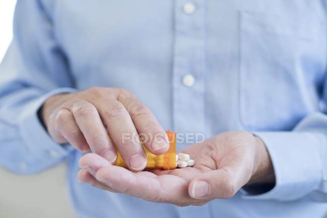 Homme versant des pilules sur la paume de la bouteille, gros plan . — Photo de stock