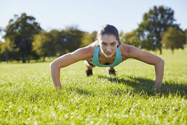 Jeune femme faisant push-up sur l'herbe . — Photo de stock