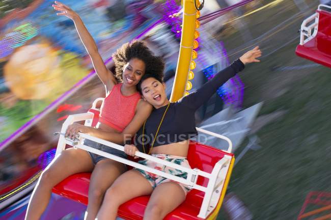 Duas jovens mulheres se divertindo no passeio de diversão . — Fotografia de Stock
