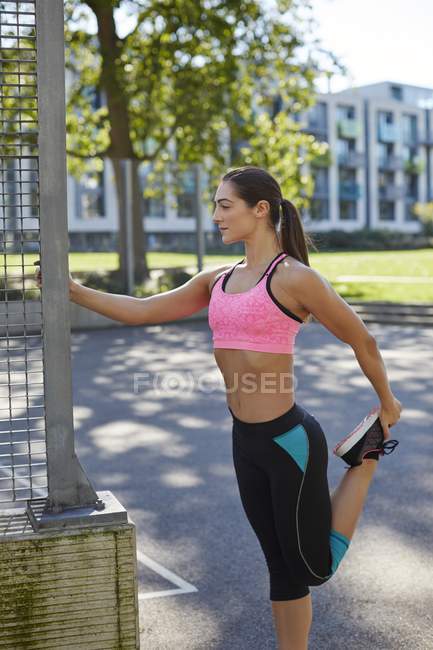 Mujer joven estirando la pierna antes del ejercicio . - foto de stock